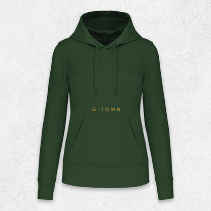 Donkergroene G‑TOWN hoodie met goudkleurige opdruk, minimalistisch gepresenteerd tegen een lichtgrijze achtergrond – duurzame streetwear met een krachtige uitstraling