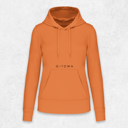 Oranje G‑TOWN hoodie met zwarte opdruk, minimalistisch gepresenteerd tegen een lichtgrijze achtergrond – duurzame streetwear met een krachtige uitstraling