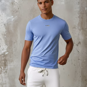 Man draagt lichtblauw heren T-shirt met minimalistisch G-TOWN logo voor een betonnen muur. G-TOWN Aqua Minimal duurzame streetwear voor heren & dames